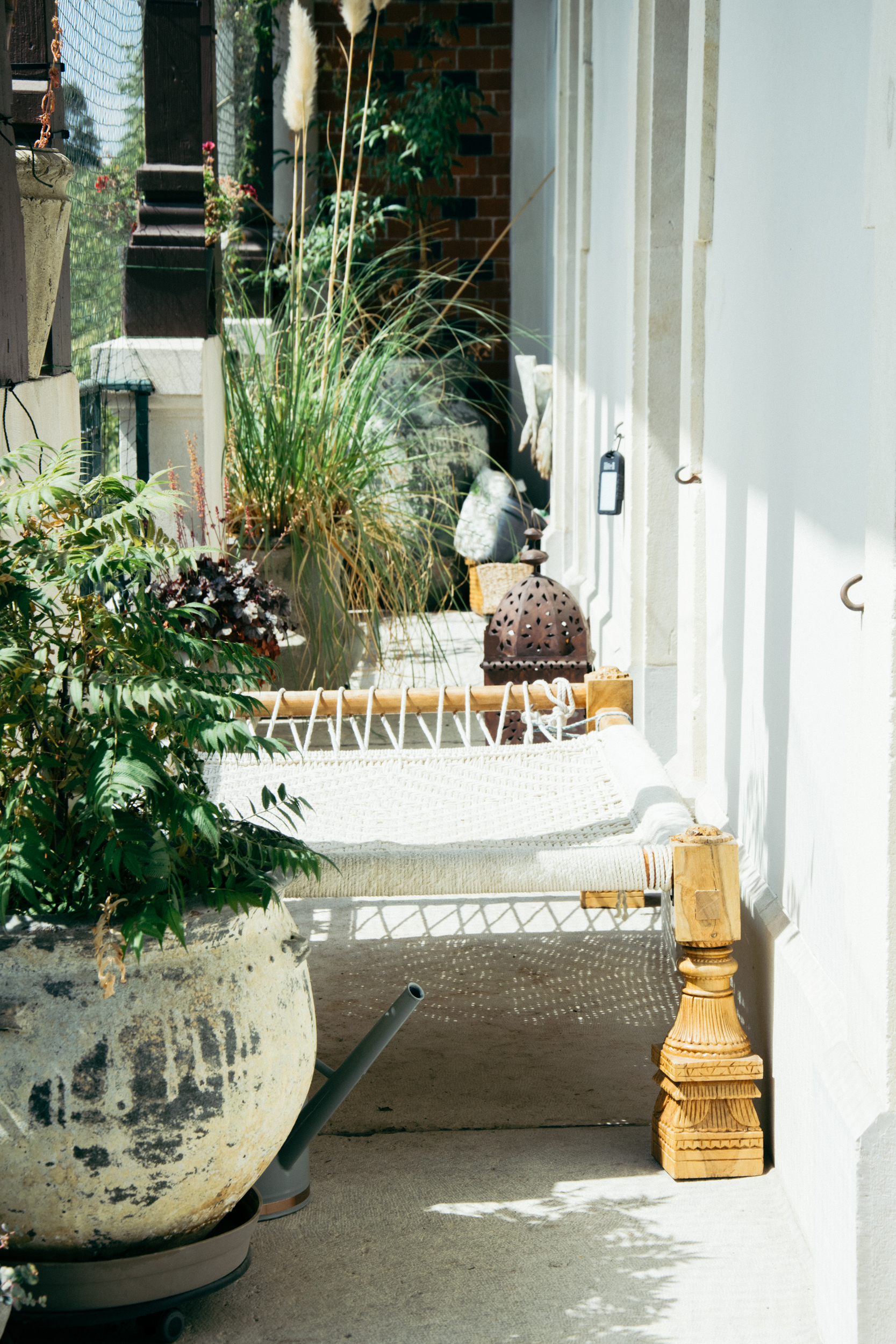 A shot of the long balcony with an Indian charpoy bed and several potted plants and trees