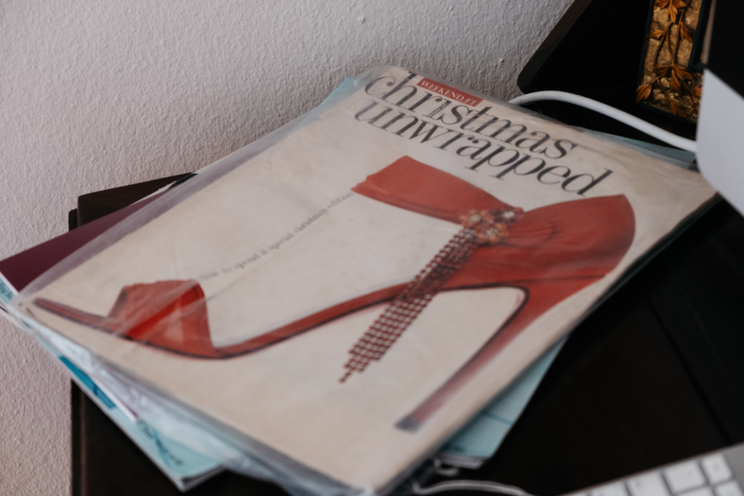 A plastic wrapped magazine by the Financial Times featuring a Christian Louboutin red silk shoe with long dangling chrystal adormnent on the cover
