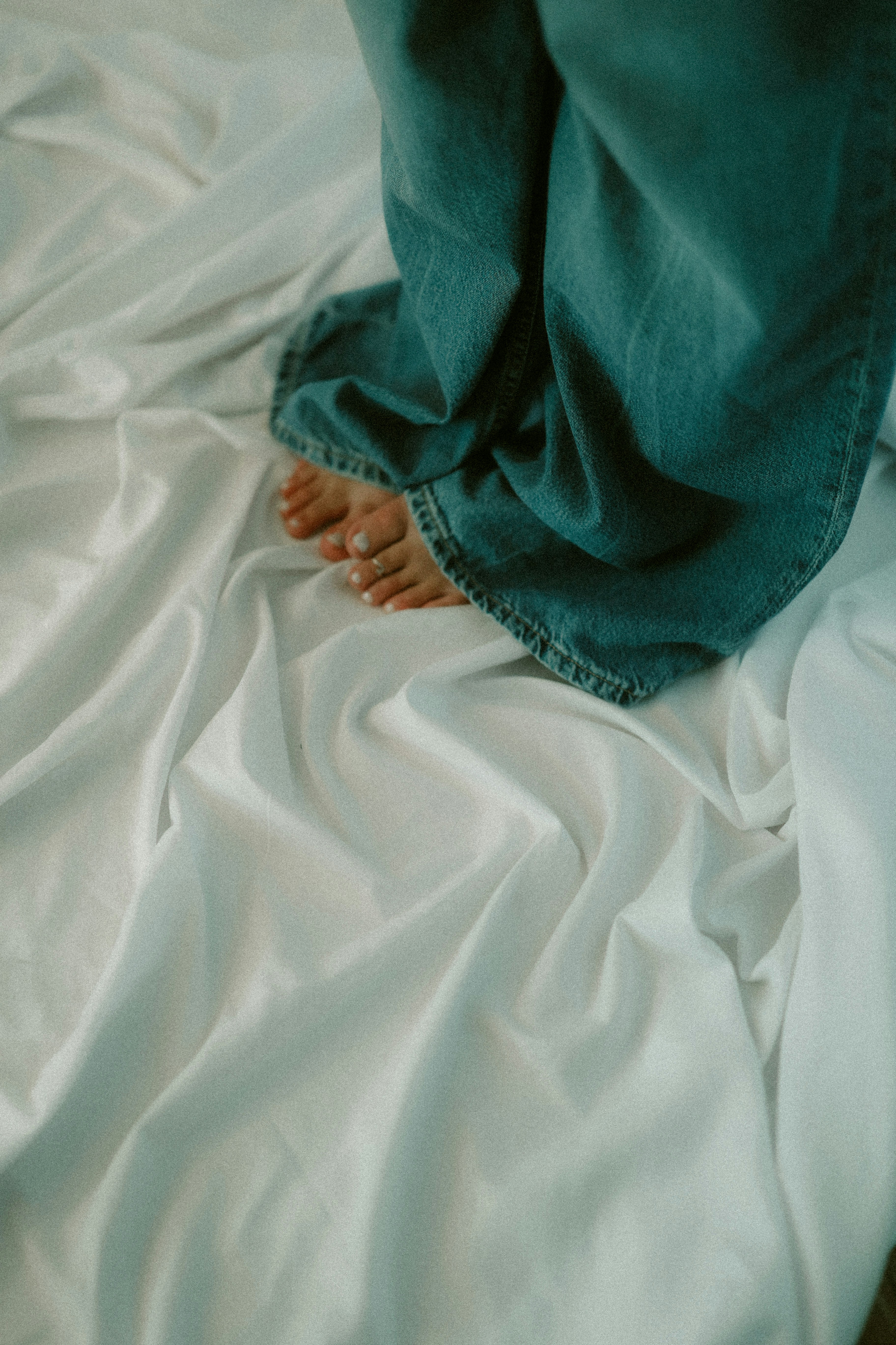 picture of someone standing on a clean white sheet, bare toes and in jeans