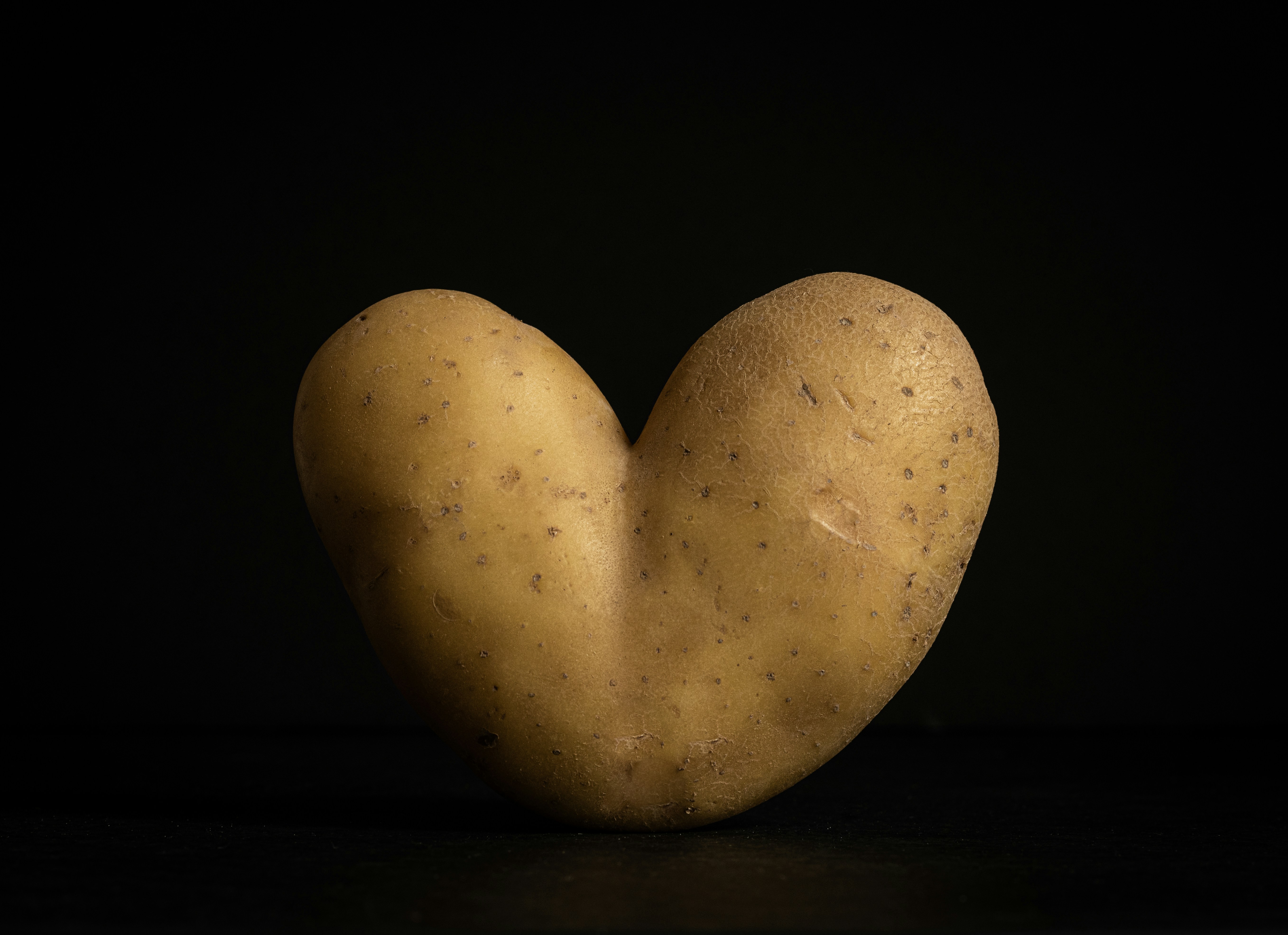 A potato in the shape of a heart on a black background