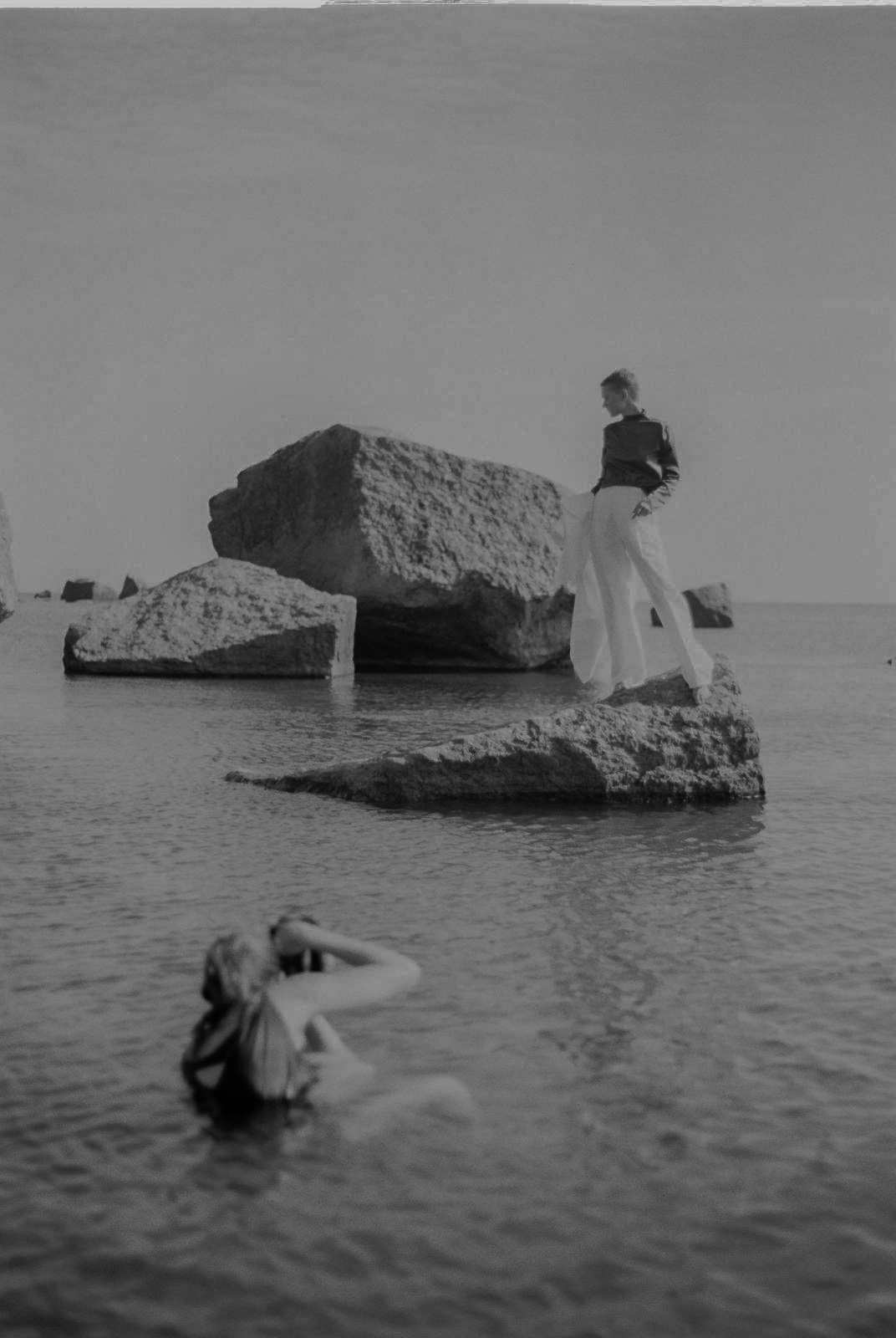 Photographer Julia Astok shooting a model standing on a rock while she is crouching in water